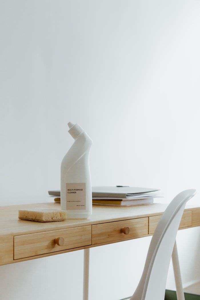 A tidy, well-arranged home office desk featuring a cleaner bottle and sponge, highlighting ease and practicality.